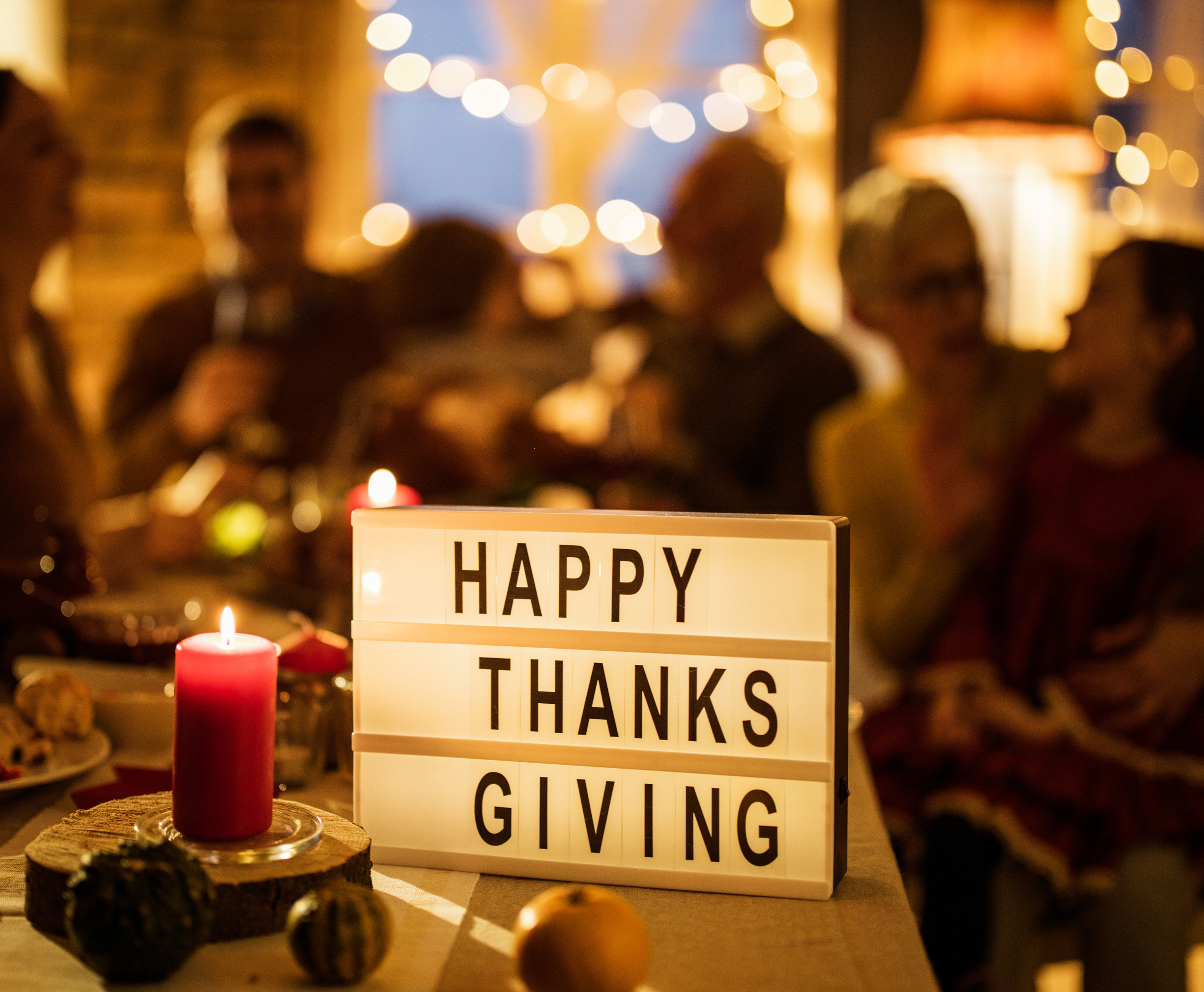 Happy Thanksgiving sign in front of people sitting at table